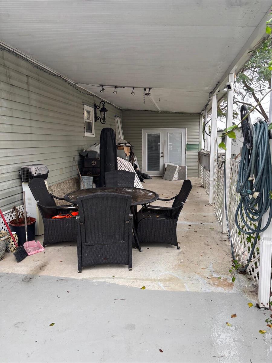 A covered outdoor patio features a dining set, a hose, and light green siding — 321 NW 48th Court, Pompano Beach FL 33064, POMPANO BEACH, FL