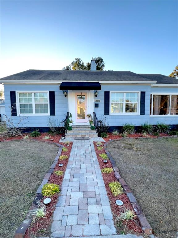 A light blue house features a brick walkway leading to a front door with a canopy — 701 PARK HILL AVE, LAKELAND, FL