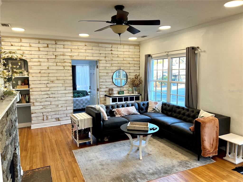 A living room features a black sectional sofa, wood-plank accent wall, and hardwood floors — 701 PARK HILL AVE, LAKELAND, FL