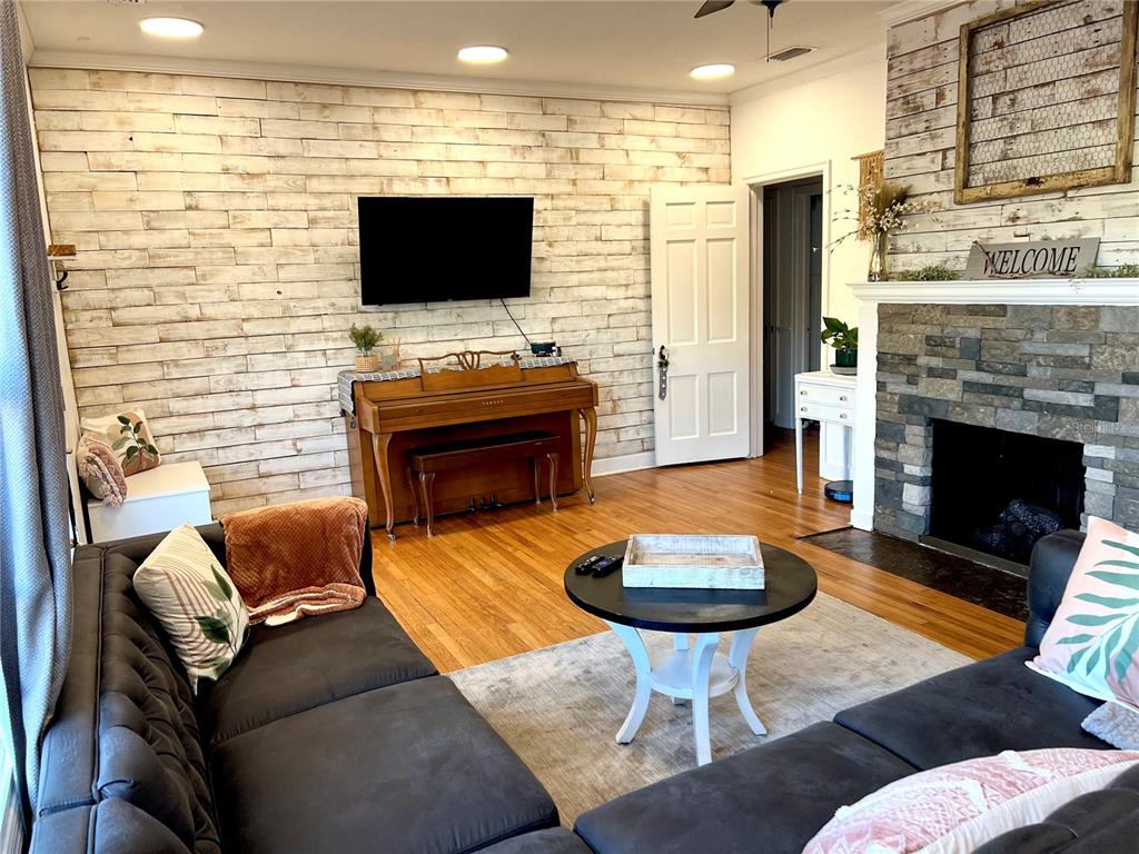 A living room features a shiplap accent wall, a stone fireplace, and a wooden piano — 701 PARK HILL AVE, LAKELAND, FL
