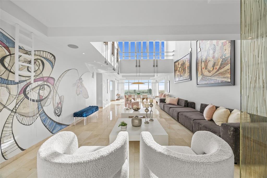 A spacious, modern living room features a large wall mural, white tile floors, and skylights — 14 RD 833, LA CIMA UNIT PH 1901, GUAYNABO, PR