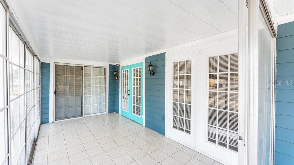 A sunroom features white tile flooring, blue siding, and multiple glass-paned doors and windows — 1214 N PINE HILLS ROAD, ORLANDO, FL