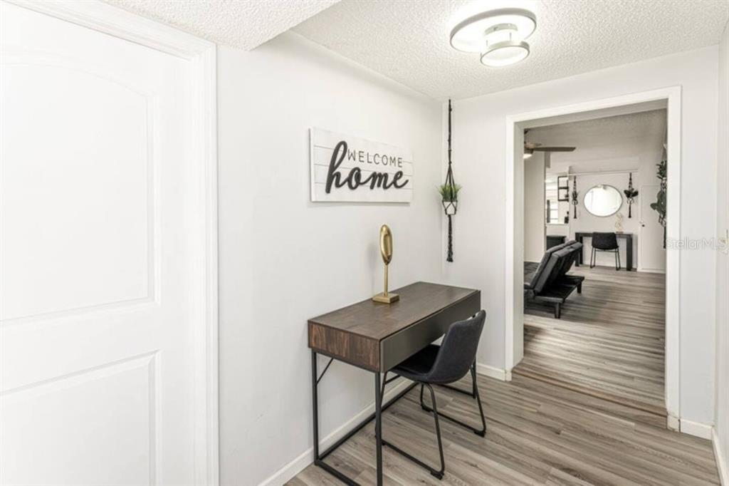 A hallway features a desk, a chair, a wall sign, and a doorway to another room — 1214 N PINE HILLS ROAD, ORLANDO, FL