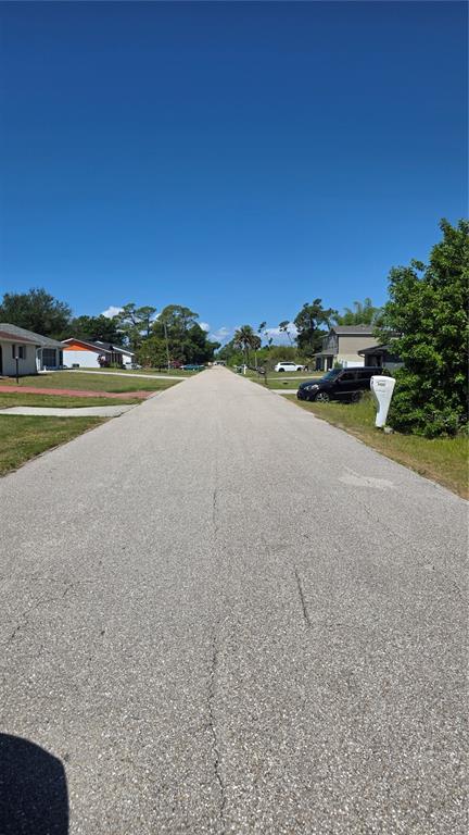 A paved residential street stretches into the distance under a clear blue sky — 22344 BUFFALO AVENUE, PORT CHARLOTTE, FL