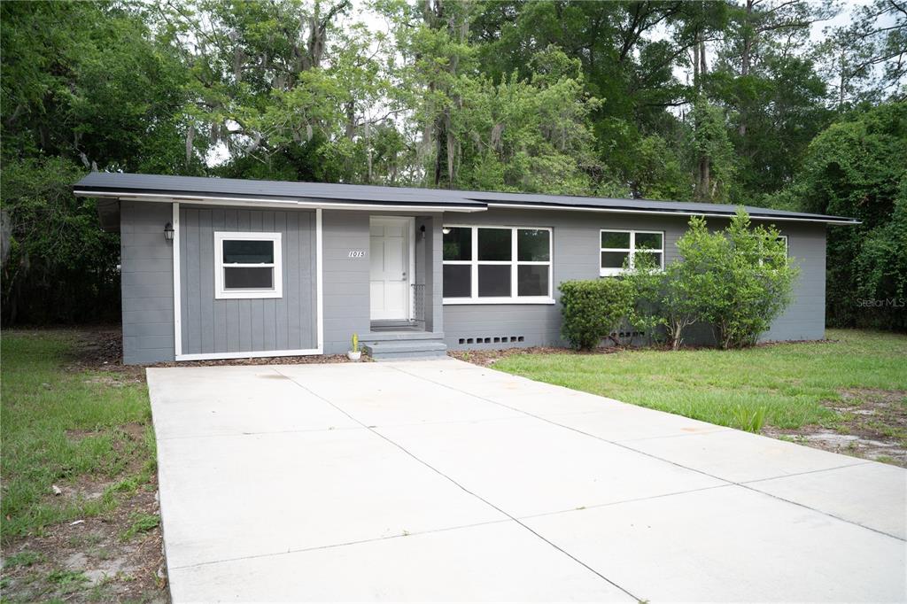 A gray, single-story house with a white front door and a concrete driveway — 1015 SE 10TH TERRACE, GAINESVILLE, FL