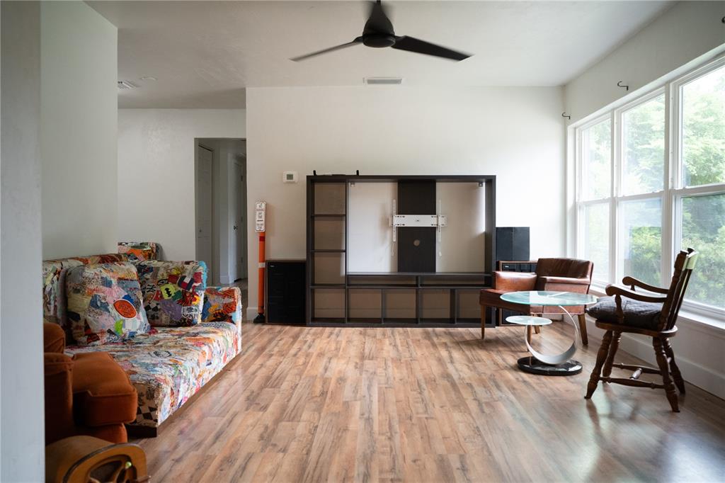A living room features wood-look flooring, a ceiling fan, a large media console, and windows — 1015 SE 10TH TERRACE, GAINESVILLE, FL