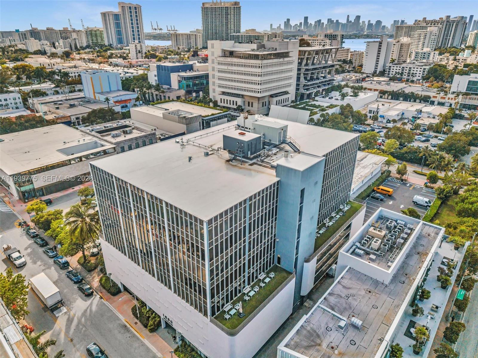 An aerial view shows a modern office building with a glass facade and rooftop terrace — 1680 Michigan Ave, Miami Beach FL 33139, MIAMI BEACH, FL