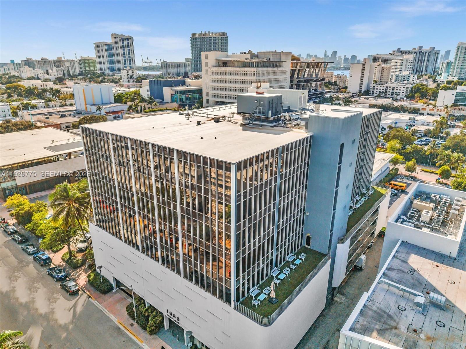 An aerial view of a modern office building with a glass facade and rooftop terrace — 1680 Michigan Ave, Miami Beach FL 33139, MIAMI BEACH, FL