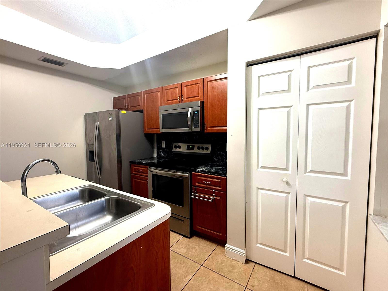 A kitchen features wood cabinets, stainless steel appliances, a double sink, and tile flooring — 4932 Windward Way # 1301, Dania Beach FL 33312, DANIA BEACH, FL