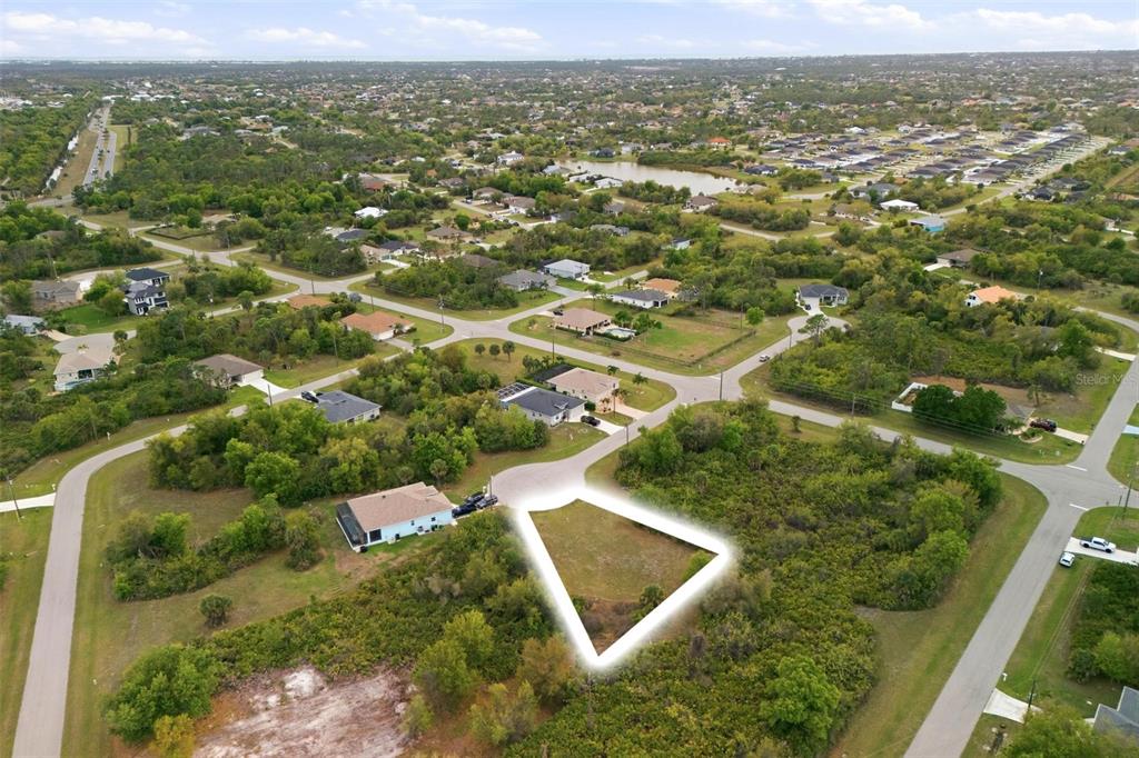 An aerial view shows a vacant, triangular-shaped residential lot outlined in white — 118 DELWAY WAY, ROTONDA WEST, FL