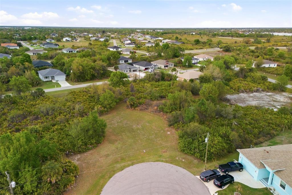 An aerial view shows a vacant, grassy residential lot situated at the end of a cul-de-sac — 118 DELWAY WAY, ROTONDA WEST, FL