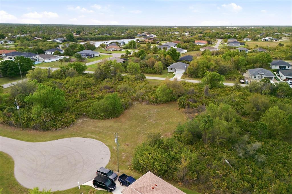 An aerial view shows a vacant residential lot surrounded by trees and nearby houses — 118 DELWAY WAY, ROTONDA WEST, FL