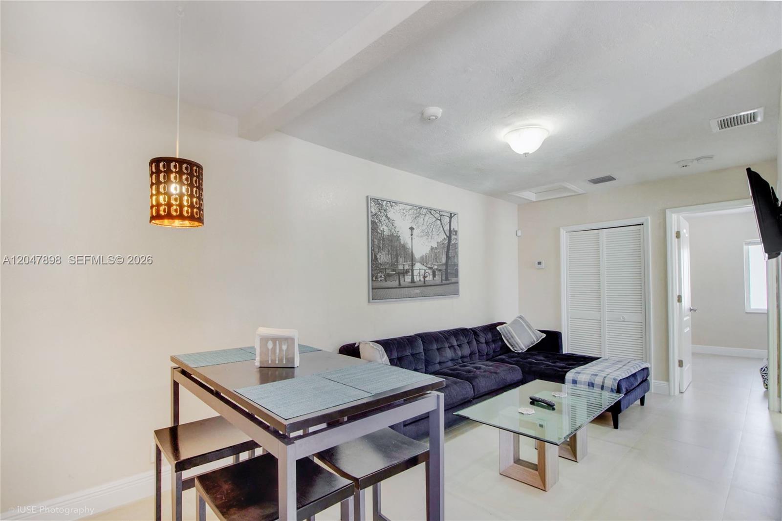 A living room and dining area featuring a dark sofa, glass coffee table, and pendant light — 518 SW 7th Ave # 520, Miami FL 33130, MIAMI, FL
