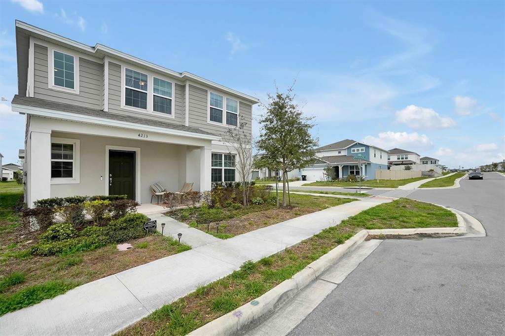 A two-story house with gray siding and a covered front porch sits on a corner lot — 4213 WINDING PINES DRIVE, APOPKA, FL