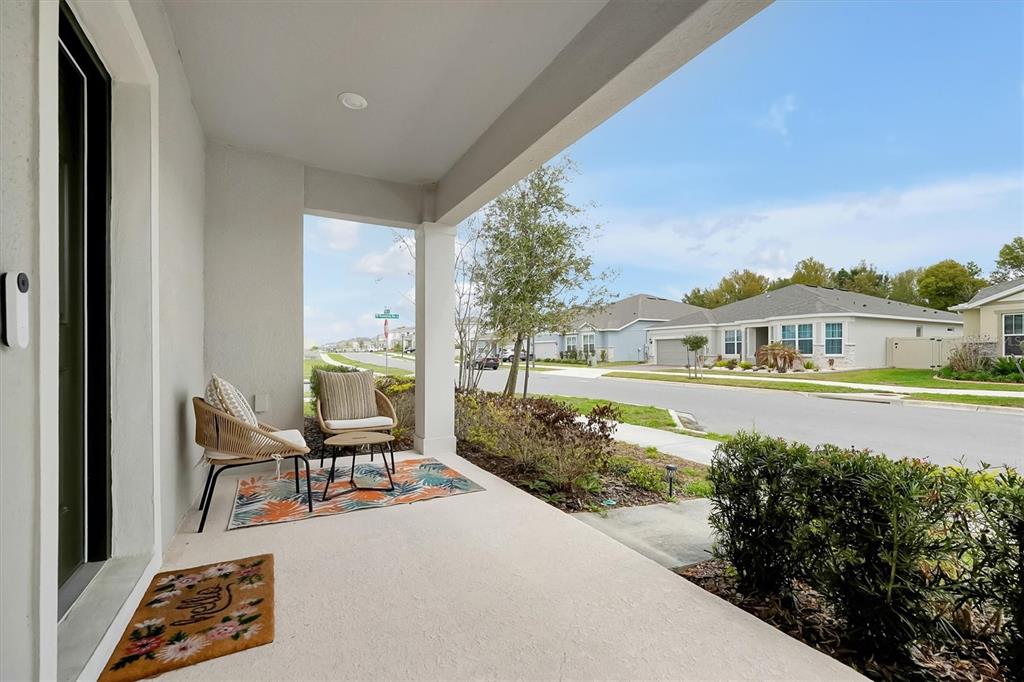 A covered front porch features two chairs on a patterned rug and a welcome mat — 4213 WINDING PINES DRIVE, APOPKA, FL