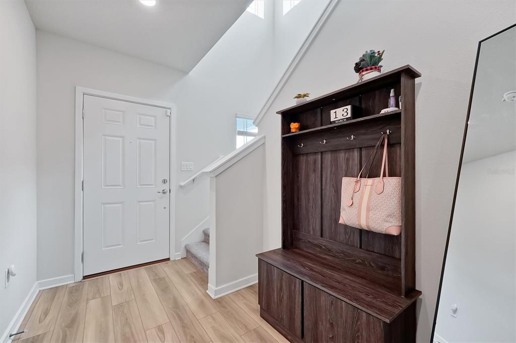 An entryway features light wood flooring, a white front door, stairs, and a wooden hall tree — 4213 WINDING PINES DRIVE, APOPKA, FL