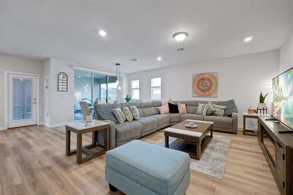 A living room features a large gray sectional sofa, a coffee table, and wood-look flooring — 4213 WINDING PINES DRIVE, APOPKA, FL