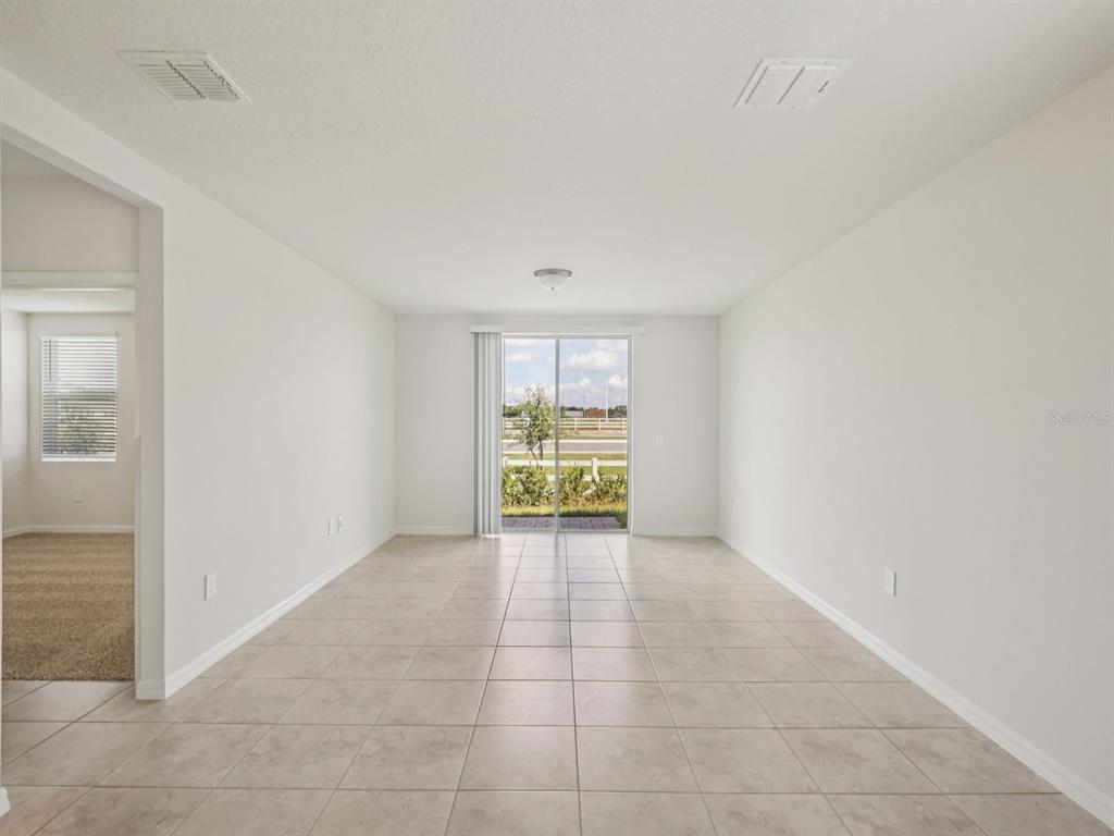 A bright, empty room with light-colored tile flooring and a sliding glass door to outside — 3865 GIORGIO DRIVE, WINTER HAVEN, FL