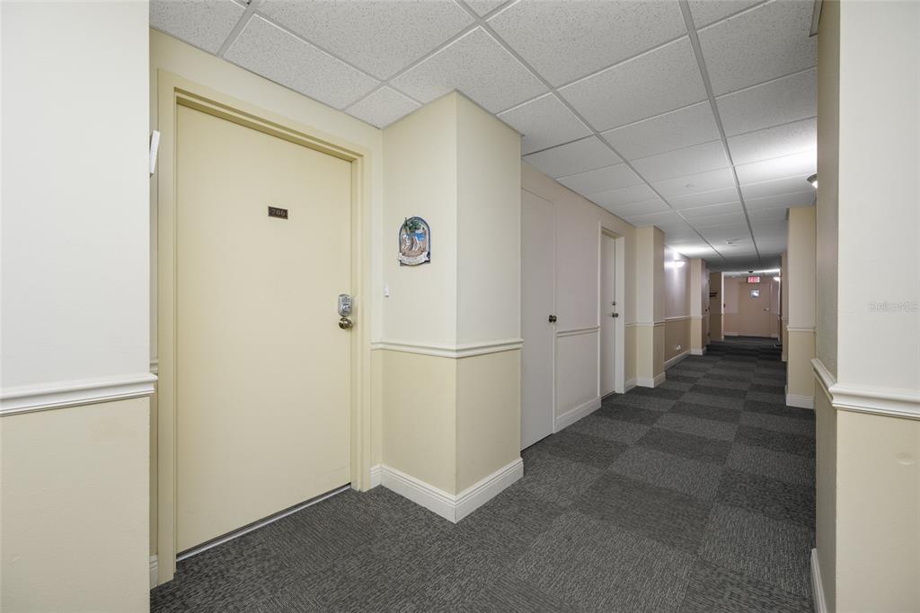 A carpeted hallway features light-colored walls, a drop ceiling, and several closed unit doors — 1621 GULF BOULEVARD UNIT 706, CLEARWATER BEACH, FL