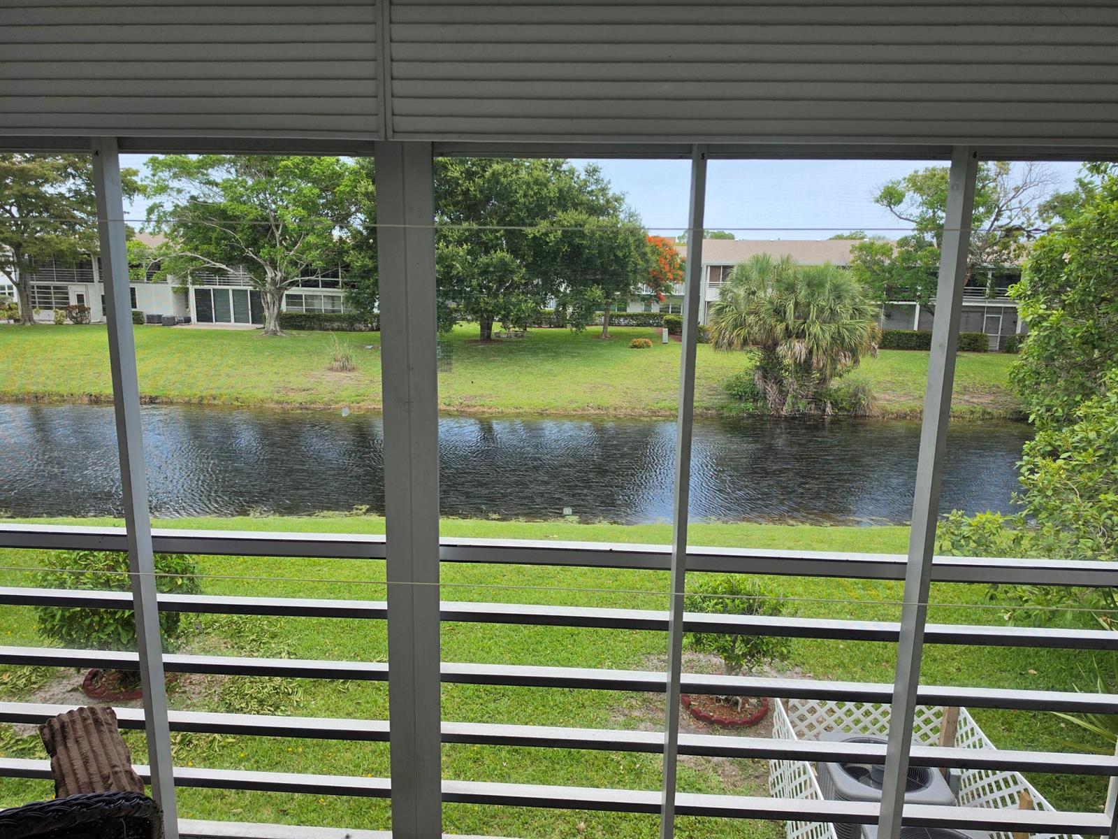 View of a canal and green lawn from a screened-in porch with metal railings — 15 Markham # A, Deerfield Beach FL 33442, DEERFIELD BEACH, FL