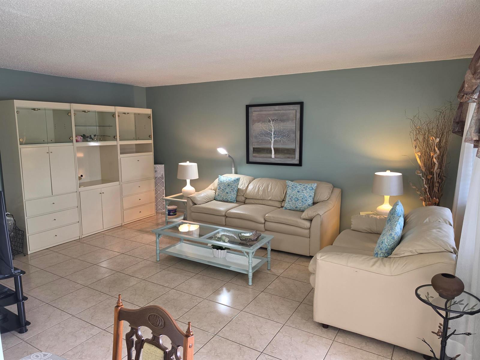 A living room features light-colored leather sofas, a glass coffee table, and a large wall unit — 15 Markham # A, Deerfield Beach FL 33442, DEERFIELD BEACH, FL