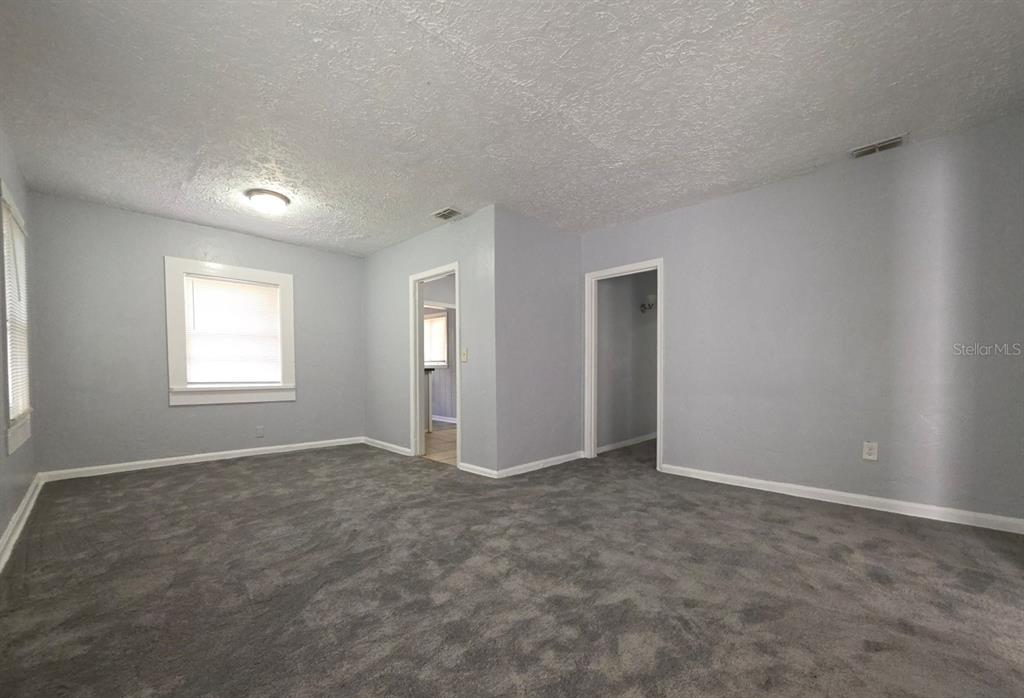 A room with gray walls, gray carpet, a ceiling light, and two doorways — 1816 E 27TH STREET, JACKSONVILLE, FL
