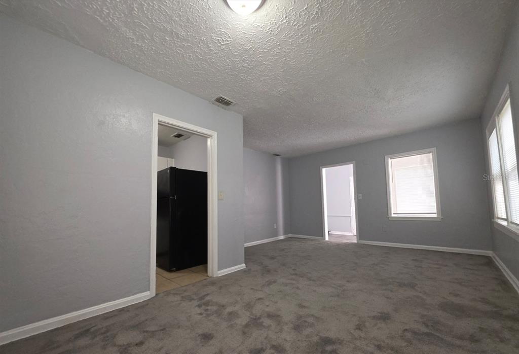 A living room with gray carpet, light blue walls, and two doorways leading to other rooms — 1816 E 27TH STREET, JACKSONVILLE, FL