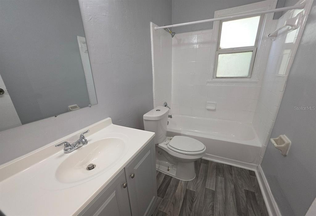 A bathroom features a vanity, a toilet, and a shower-tub combination with white tile walls — 1816 E 27TH STREET, JACKSONVILLE, FL