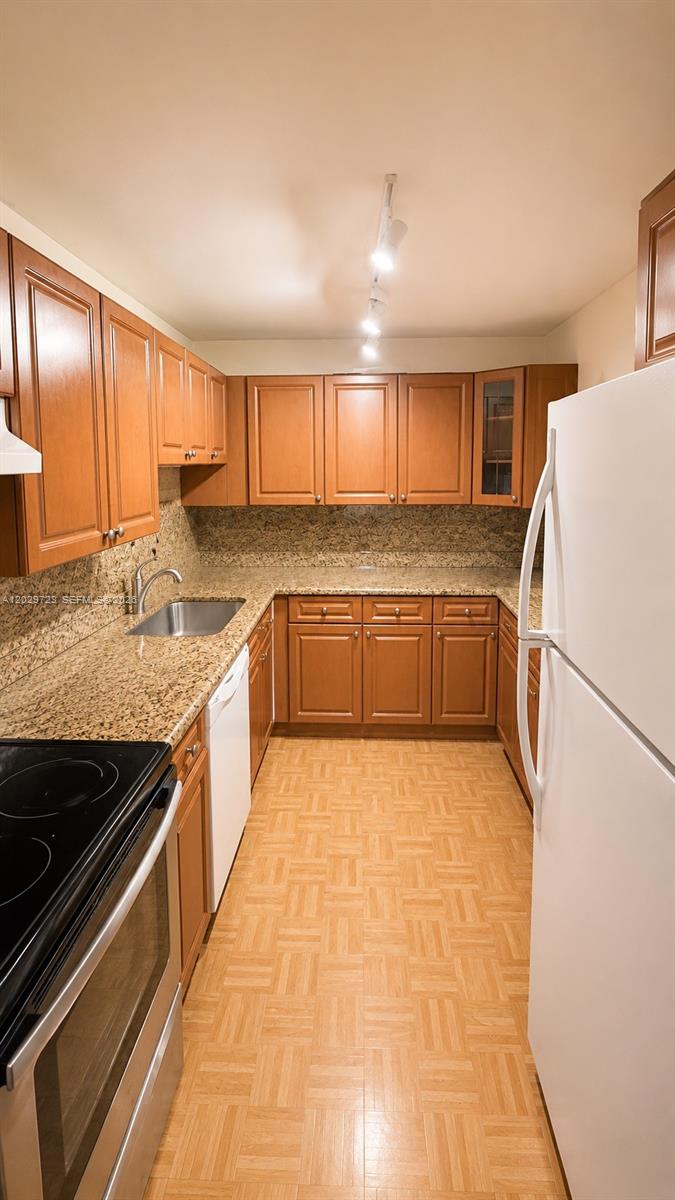 A galley kitchen features wood cabinets, granite countertops, a white refrigerator, and parquet flooring — 8520 SW 133rd Ave Rd # 210, Miami FL 33183, MIAMI, FL
