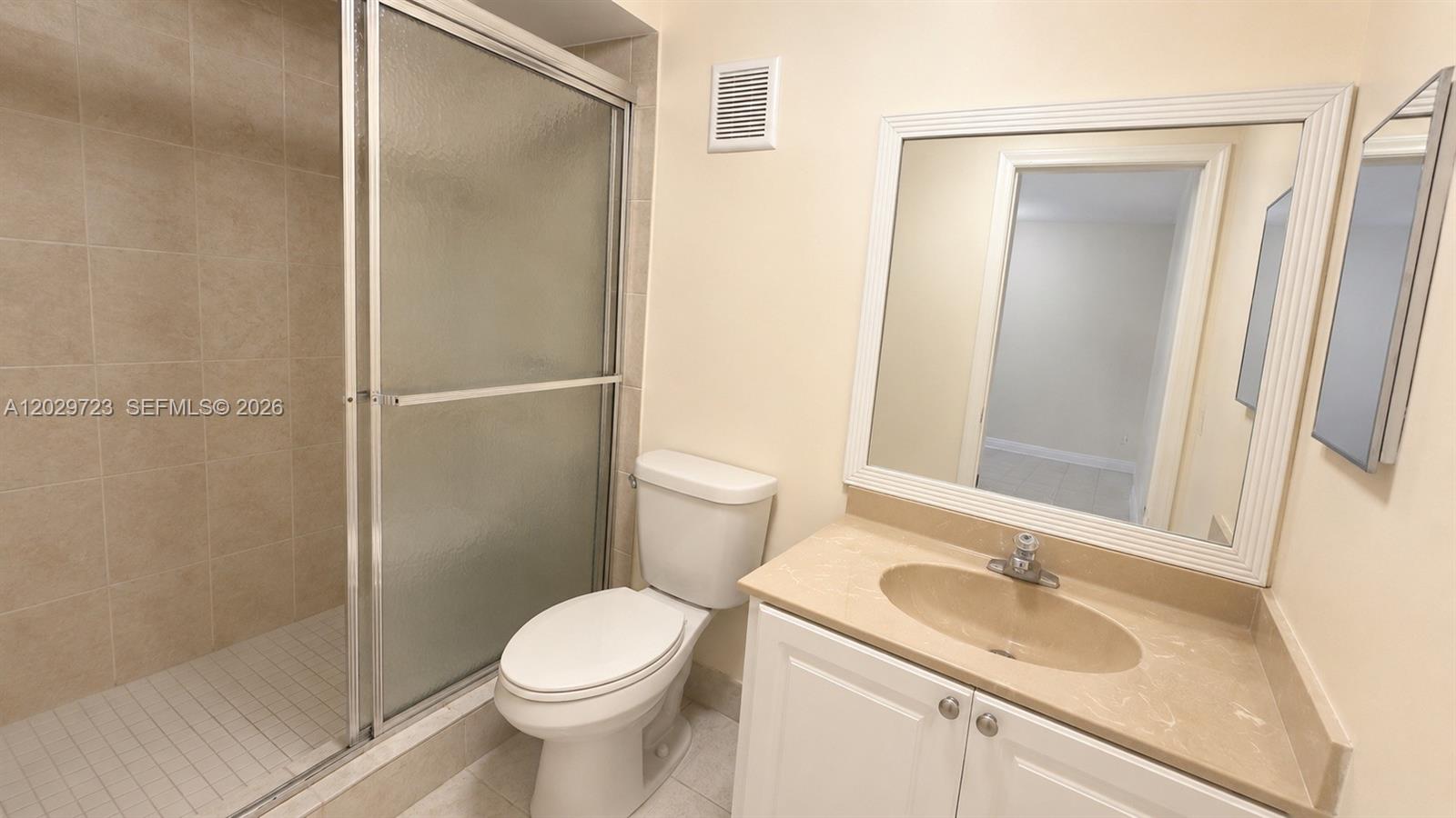 A bathroom features a walk-in shower, a white toilet, and a vanity with a mirror — 8520 SW 133rd Ave Rd # 210, Miami FL 33183, MIAMI, FL