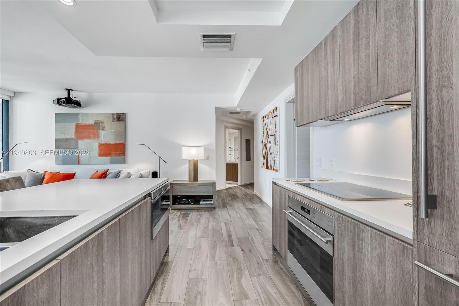 A modern kitchen features wood-grain cabinetry, stainless steel appliances, and a white island countertop — 801 S Miami Ave # 2905, Miami FL 33130, MIAMI, FL