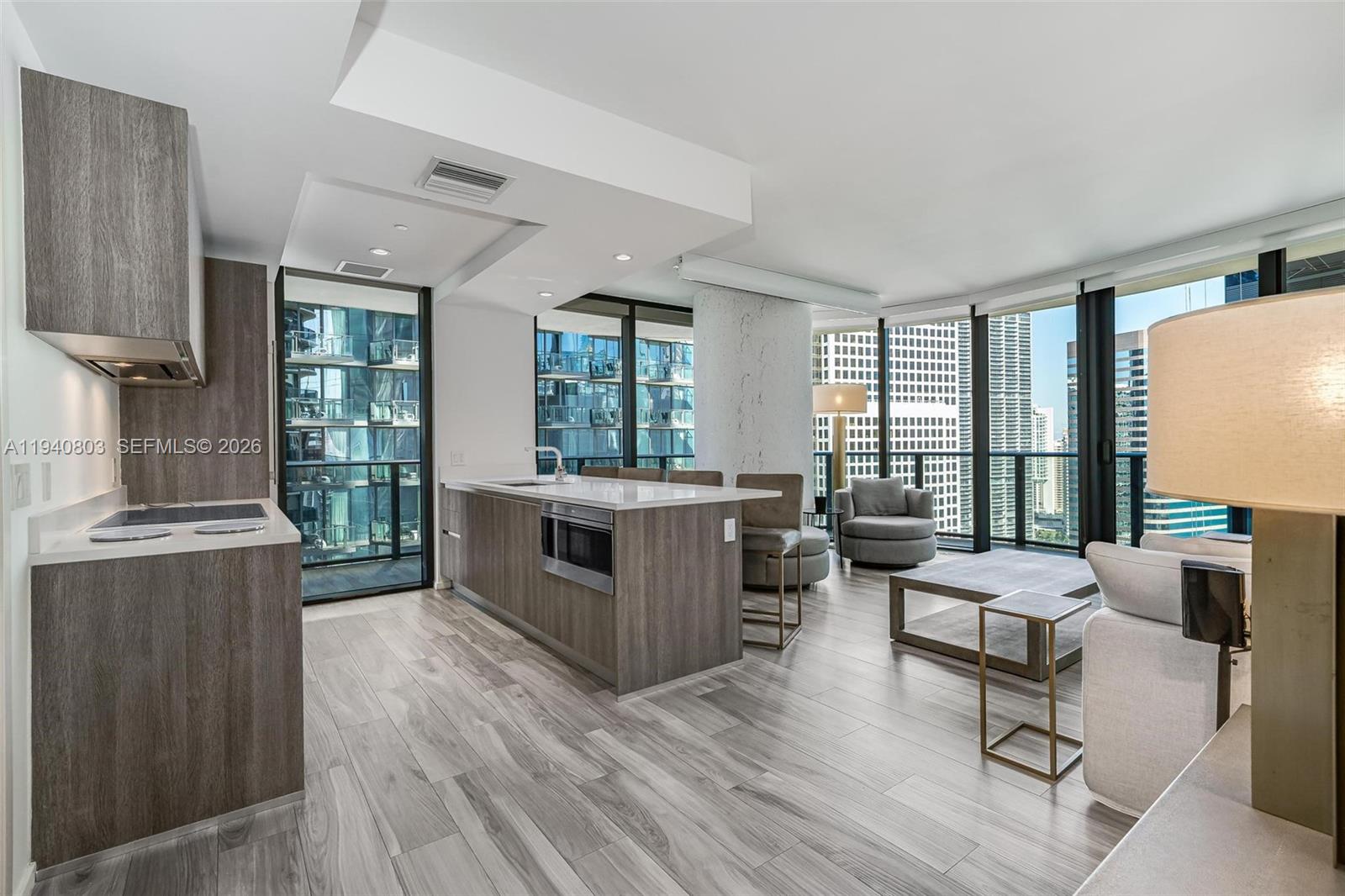 A modern open-concept kitchen and living area features wood cabinetry, stone countertops, and floor-to-ceiling windows — 801 S Miami Ave # 2905, Miami FL 33130, MIAMI, FL