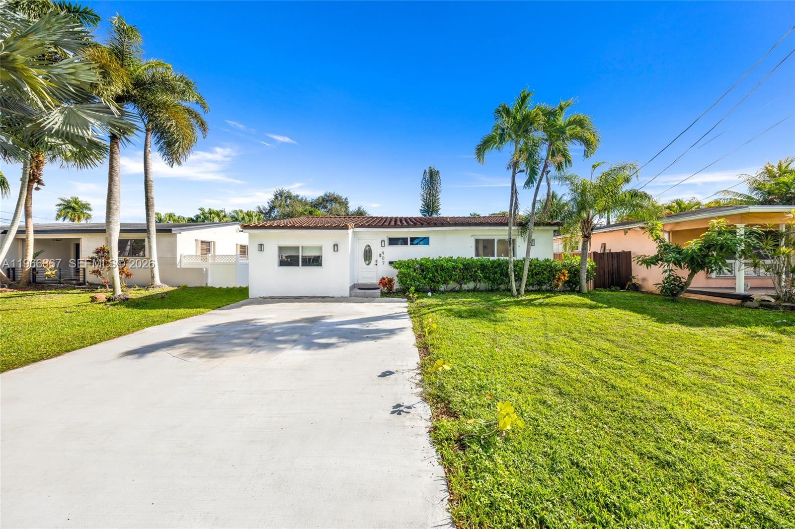 A single-story white house with a concrete driveway and palm trees under a blue sky — 907 N Park Rd, Hollywood FL 33021, HOLLYWOOD, FL