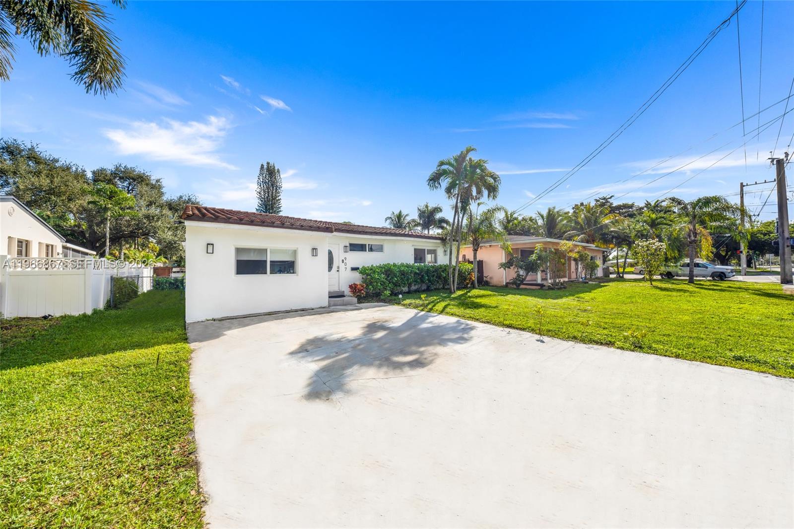 A single-story white house with a concrete driveway and palm trees under a blue sky — 907 N Park Rd, Hollywood FL 33021, HOLLYWOOD, FL