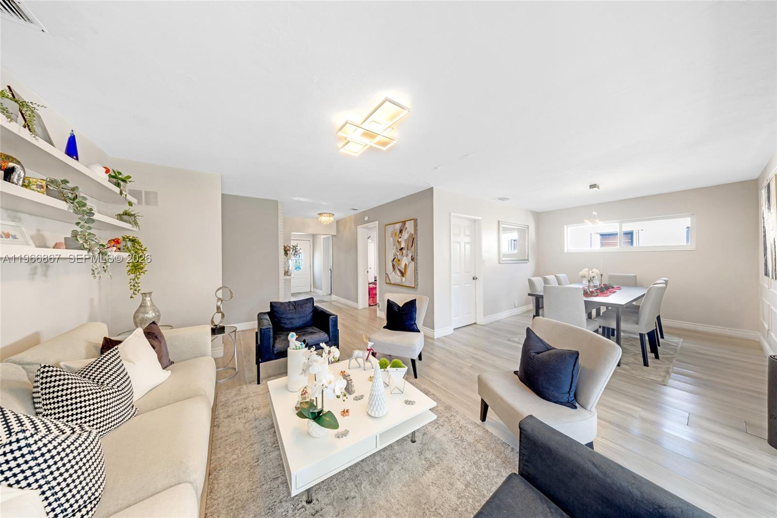 A living room and dining area feature light wood floors, neutral walls, and modern furniture — 907 N Park Rd, Hollywood FL 33021, HOLLYWOOD, FL