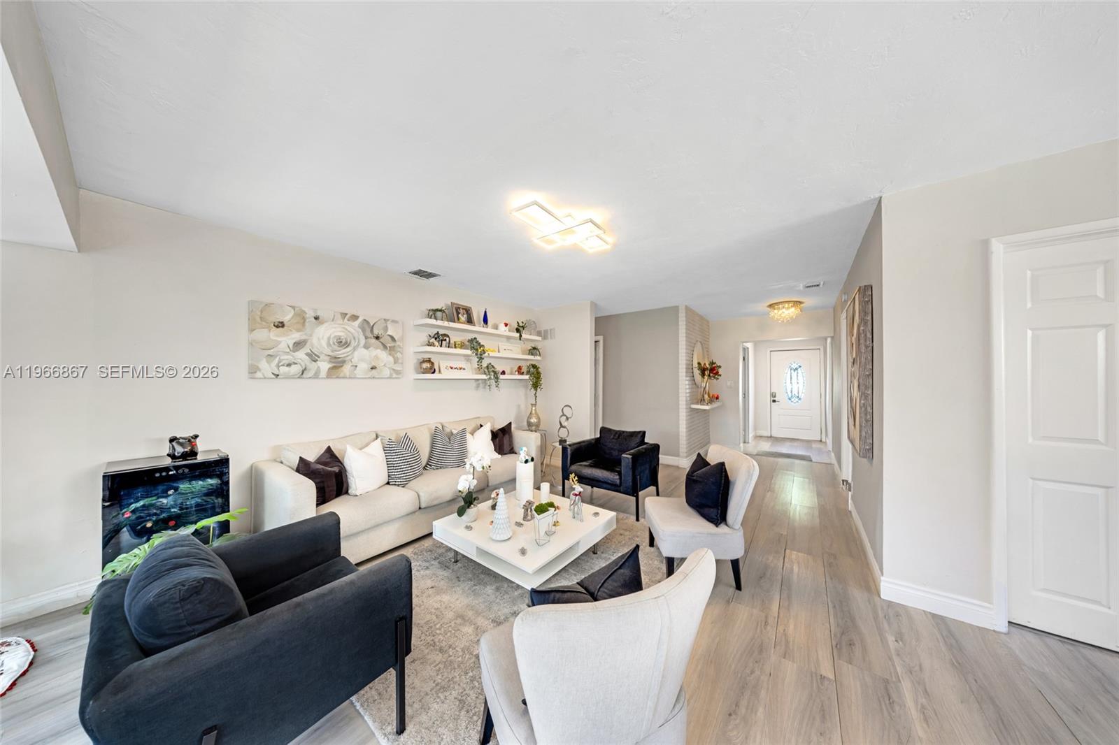 A living room features a white sofa, accent chairs, a coffee table, and wall shelving — 907 N Park Rd, Hollywood FL 33021, HOLLYWOOD, FL