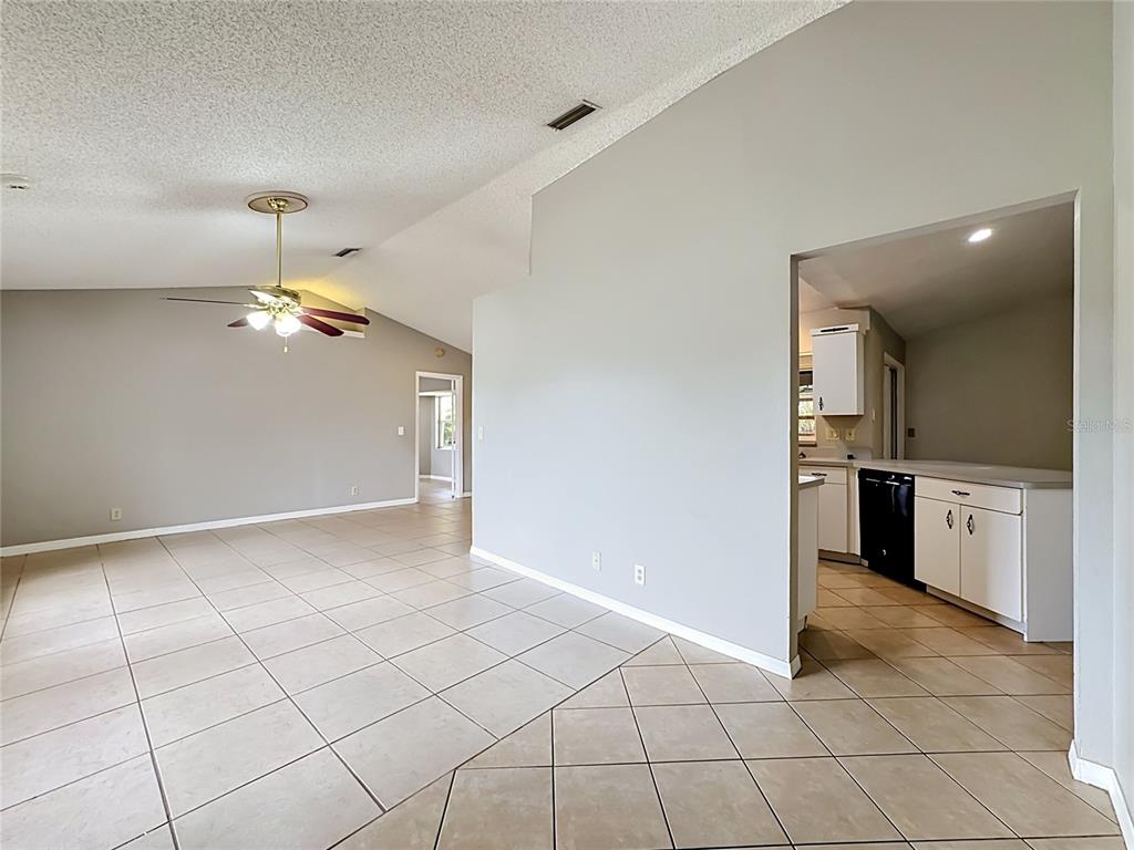 An open-concept living area with tile flooring, a vaulted ceiling, and an adjacent kitchen — 1570 S BISCAYNE DRIVE, NORTH PORT, FL