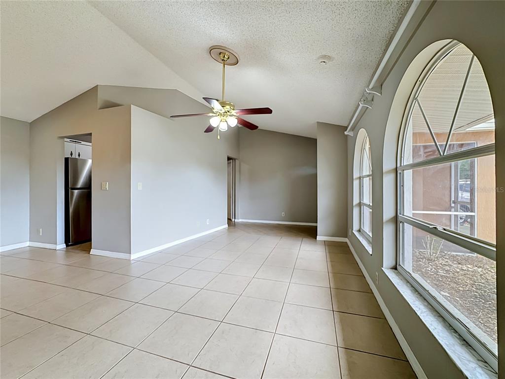 An open living area features vaulted ceilings, tile flooring, a ceiling fan, and arched windows — 1570 S BISCAYNE DRIVE, NORTH PORT, FL