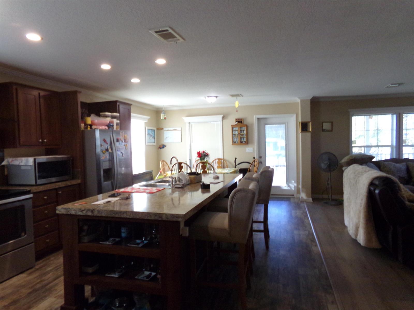 A kitchen with a large granite-topped island, dark wood cabinetry, and wood-look flooring — 147 Plantation Boulevard, FL 33467, FL