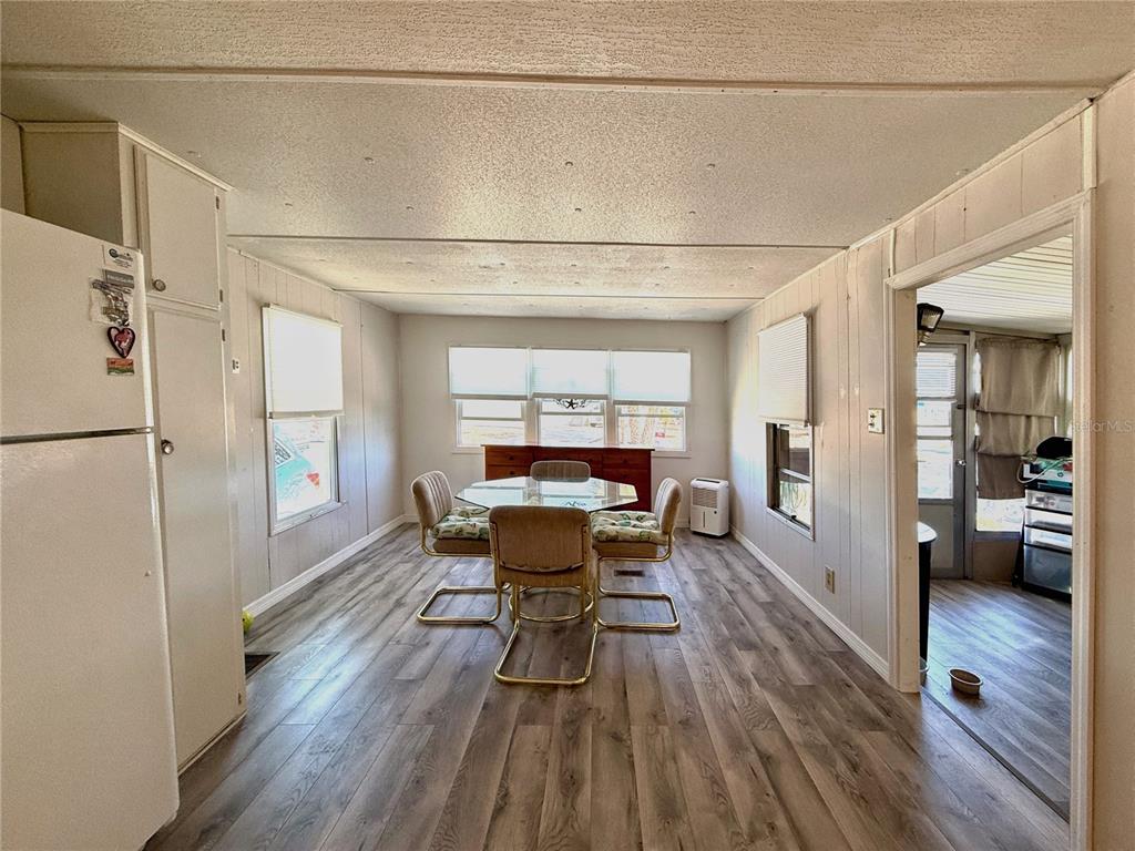 A dining area features wood-look flooring, white paneled walls, and a glass-topped table with chairs — 308 S PORT ROYAL LANE, APOLLO BEACH, FL