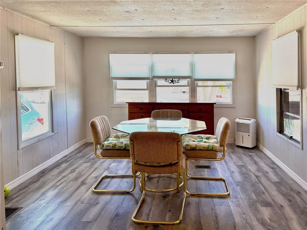 A dining room features a glass-topped table, four chairs, wood-look flooring, and three windows — 308 S PORT ROYAL LANE, APOLLO BEACH, FL