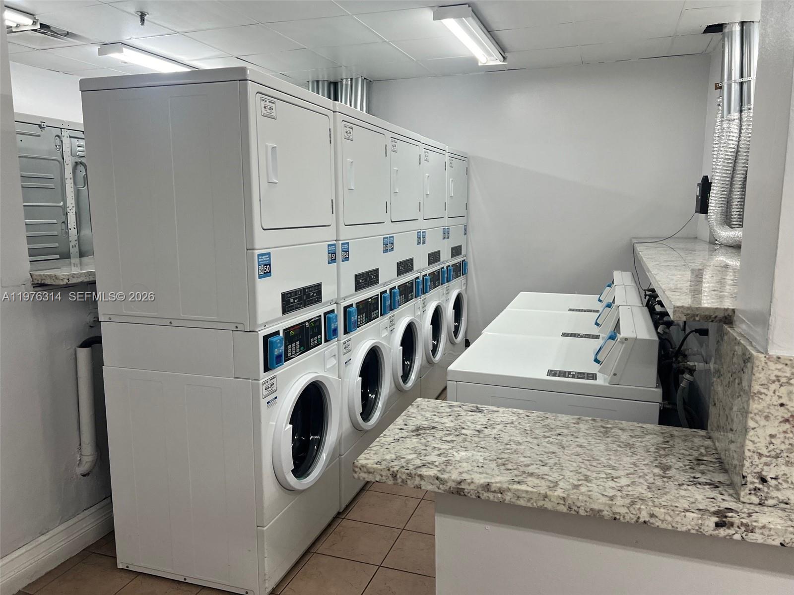 A laundry room features stacked washer-dryer units and top-loading washing machines with granite countertops — 850 N Miami Ave # 1806, Miami FL 33136, MIAMI, FL