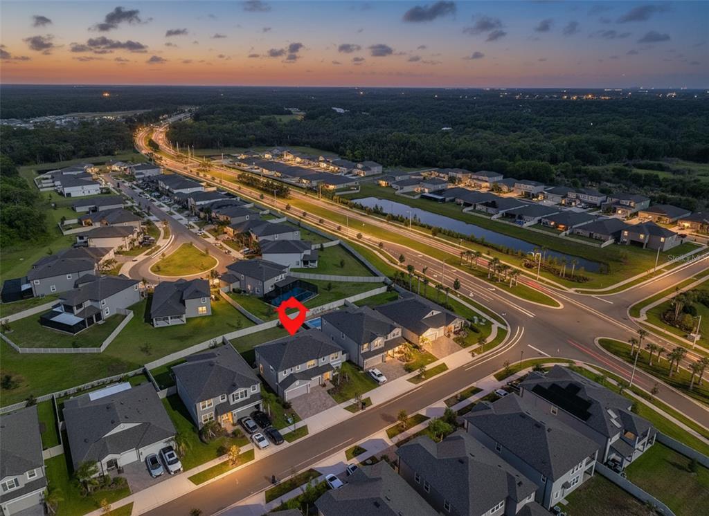 An aerial view shows a suburban neighborhood at dusk with a red marker on a house — 2927 MARINE GRASS DRIVE, WIMAUMA, FL