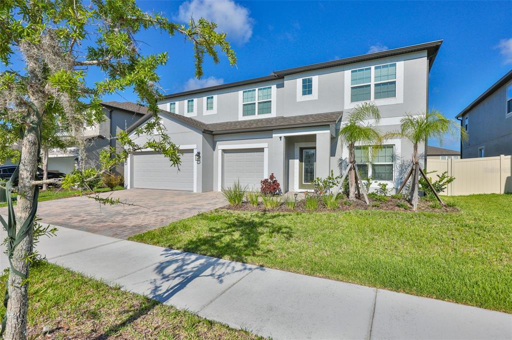 A two-story suburban house with a gray exterior, two garage doors, and a paved driveway — 2927 MARINE GRASS DRIVE, WIMAUMA, FL