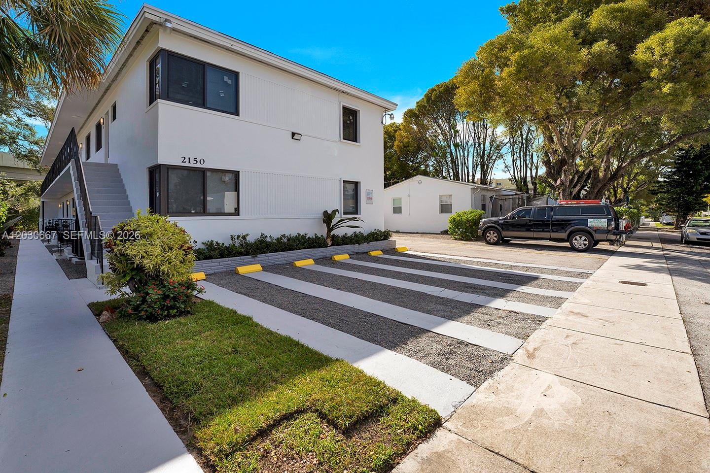 A two-story white apartment building features exterior stairs and a gravel parking area — 2150 SW 26th St # 7, Miami FL 33133, MIAMI, FL