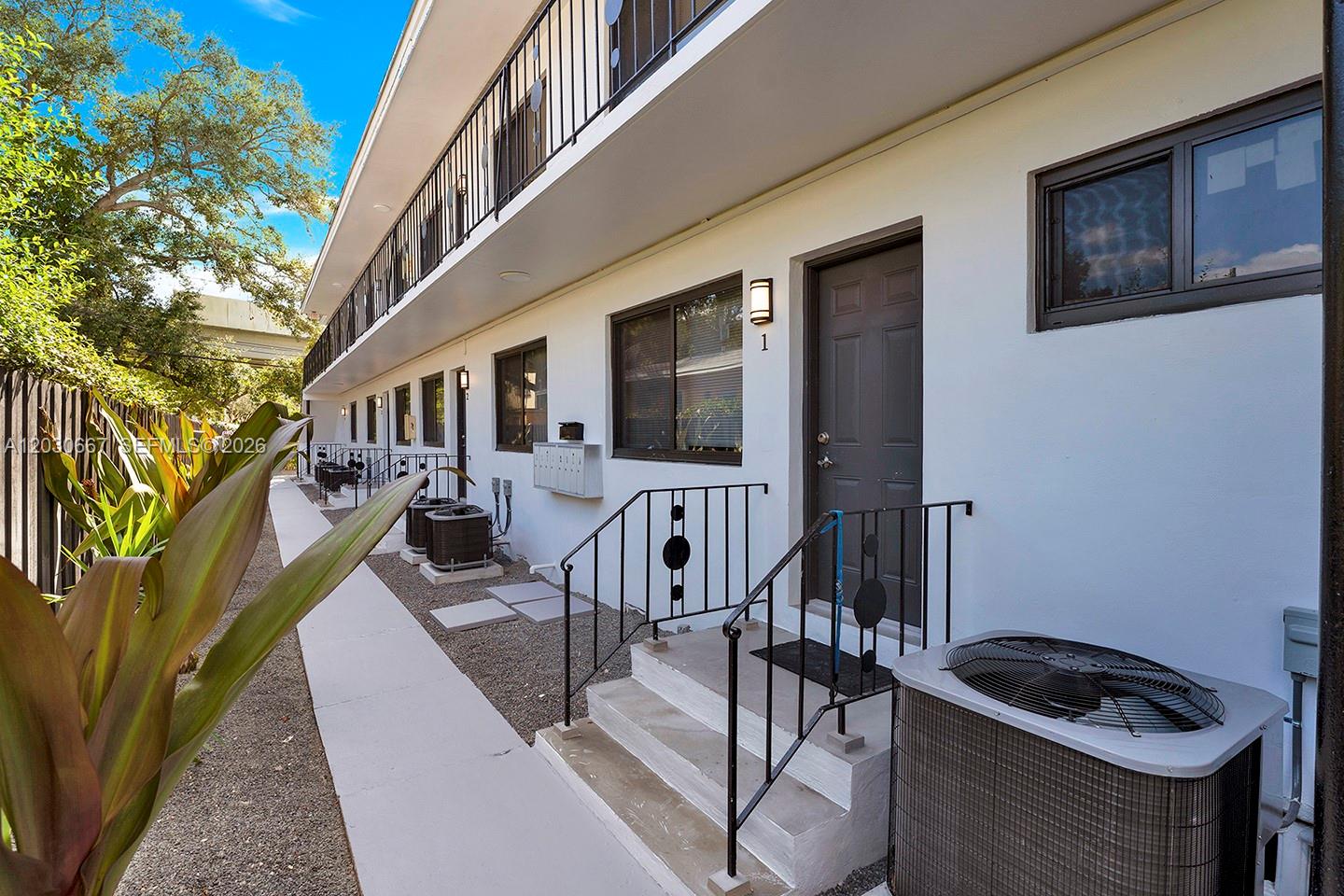 A ground-level view of a multi-unit apartment building exterior with stairs and air conditioning units — 2150 SW 26th St # 7, Miami FL 33133, MIAMI, FL