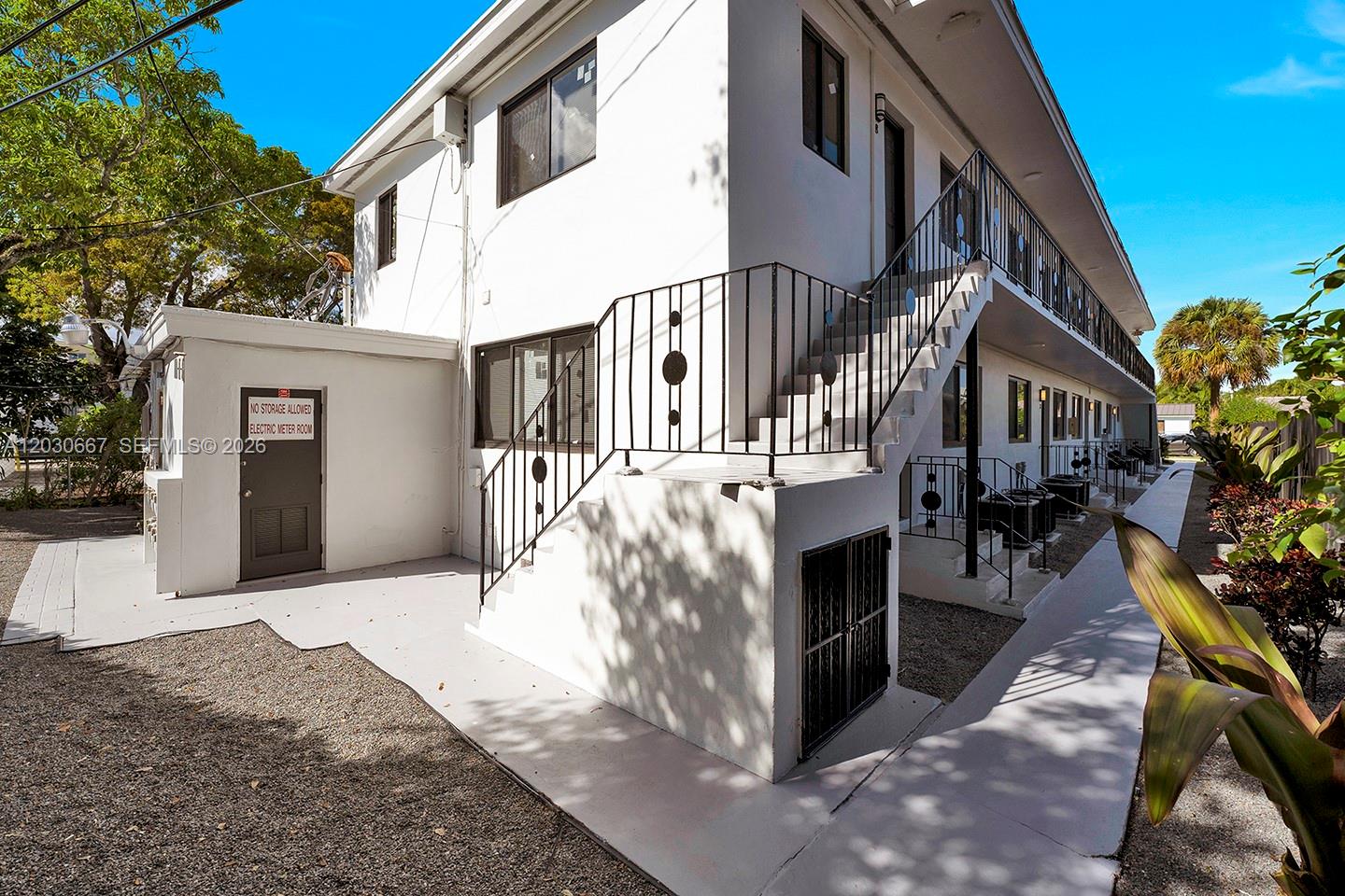 An exterior view of a two-story white apartment building with an outdoor staircase and walkway — 2150 SW 26th St # 7, Miami FL 33133, MIAMI, FL