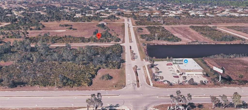 An aerial view shows a vacant, wooded lot marked with a pin near a road — 39 DECORORE DRIVE, ROTONDA WEST, FL