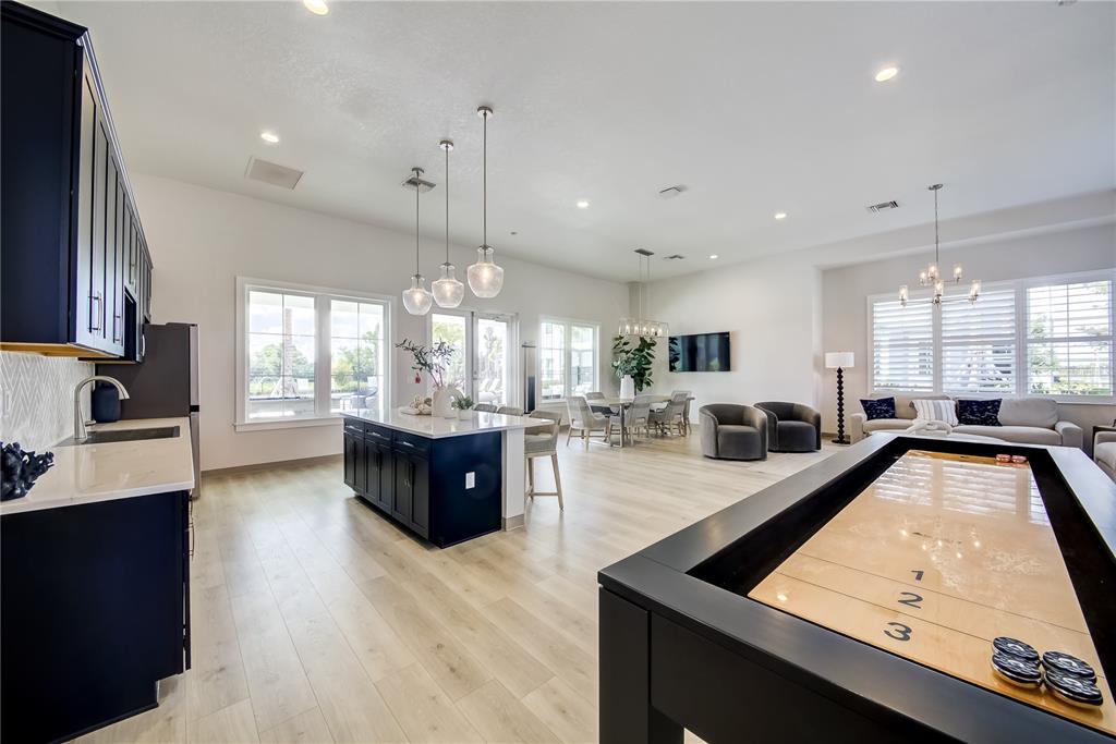 A spacious open-concept room features a kitchen island, dining area, living space, and shuffleboard table — 200 EAGLESTON LANE, LAKEWOOD RANCH, FL