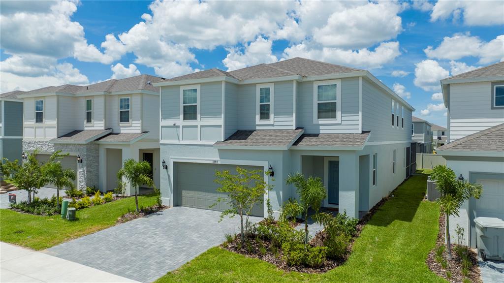A two-story light blue house with a paved driveway and a two-car garage — 3344 LILAC WAY, DAVENPORT, FL
